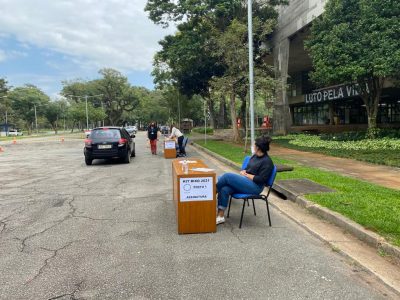 Mesas em frente à FAU e um carro ao fundo durante a entrega do kit bixo